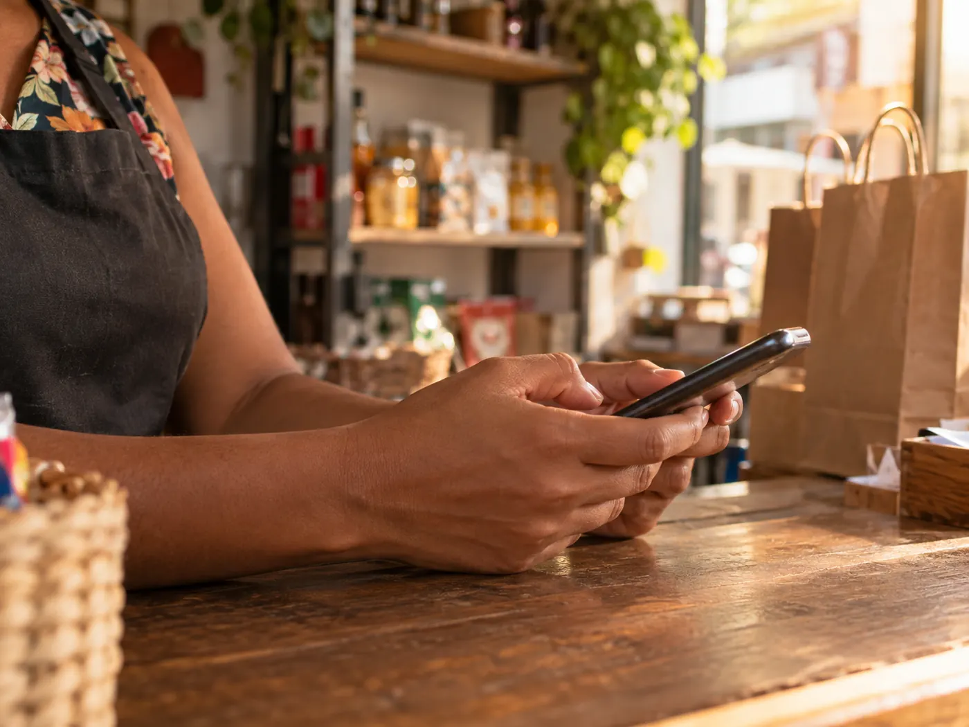 Vendedora responde mensagens no celular no balcão da loja