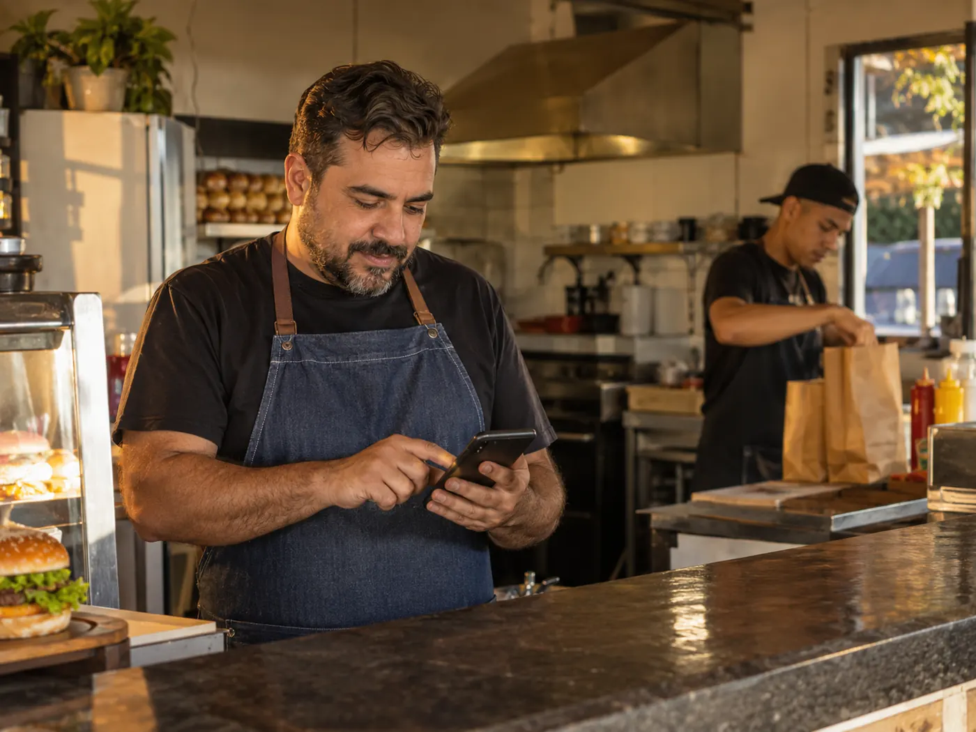 Dono de lanchonete confere pedidos no celular